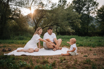 Happy family on a blanket outdoors in Luxembourg during golden hour, baby's intimate first discovery showing something to mommy.
