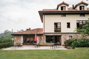 A rural hotel building in Luxembourg is shown from a lateral perspective, with its terrace and garden in the foreground.