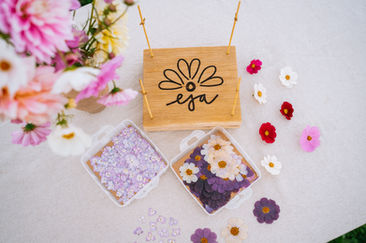 Close-up of hands arranging pressed flowers on paper, product photography Luxembourg handmade process