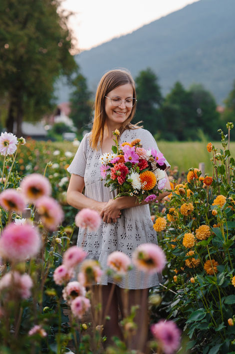 Florist smiling while holding bouquet in flower field, branding photography Luxembourg natural lifestyle