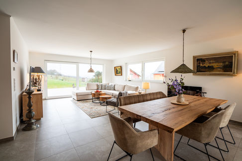 Open-plan living and dining area with large windows, real estate photography Luxembourg showcasing natural light
