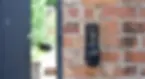 An open key safe with 4 keys inside it on a brown brick wall.
