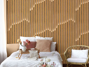 Modern bedroom with warm-toned peel-and-stick wood panel wallpaper behind bed, styled with neutral pillows and decorative accents