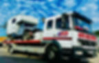 Close-up view of a recovery technician securing a vehicle on a flatbed truck