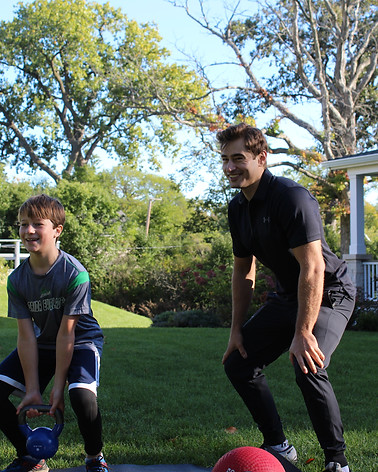 Personal trainer George Kostopoulos coaching a client through a kettlebell workout in a backyard