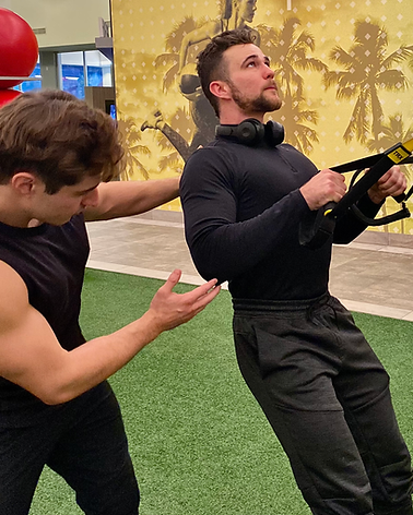 Personal trainer George Kostopoulos guiding a client through a TRX suspension row