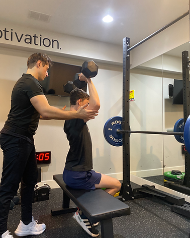 George Kostopoulos spotting a client's dumbbell shoulder press during an in-home personal training session