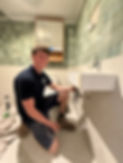 A photograph of a Flow Plumbing staf member working on installing a new sink in a bathroom.
