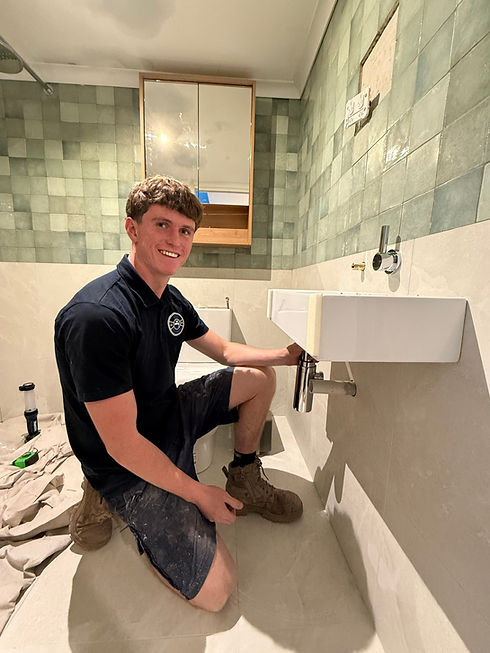A photograph of a Flow Plumbing staf member working on installing a new sink in a bathroom.