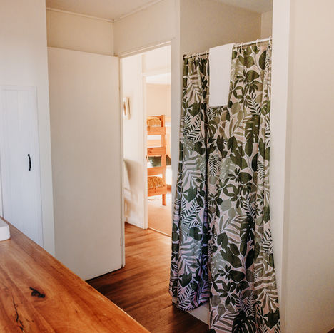 Timber cottage bathroom and laundry with toilet, shower and sink.