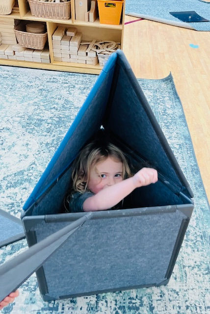 Child peeking out from inside a cozy fort built with Superspace felt panels.