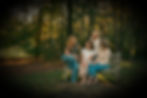 4 women sit on a bench in the forest and look at each other
