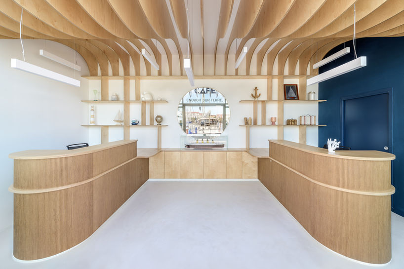 Banque d’accueil en bois de bouleau sur mesure avec plafond ondulé – aménagement des bureaux professionnels d’AMC CAPE GRACE à Saint-Raphaël par Violaine Planchard Architecture.