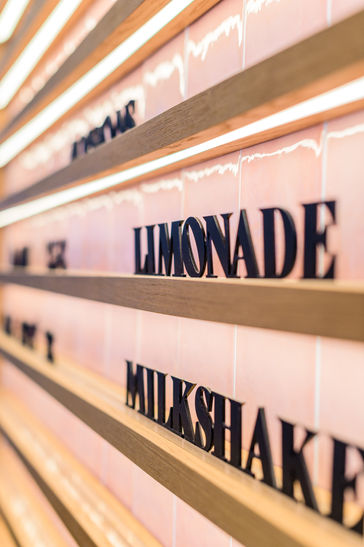 Zoom sur le lettrage en relief du menu mural – signalétique artisanale et minimaliste dans le glacier Café NOMY.