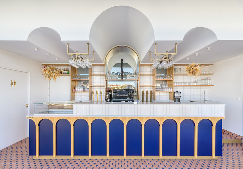 Vue d’ensemble du bar du Café Nomy avec arches bleu marine, comptoir en chêne sur mesure et plafond voûté – aménagement intérieur méditerranéen à Saint-Raphaël signé VP Architecture.