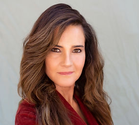 a brunette woman looks seriously yet kindly and wears a burgundy shirt