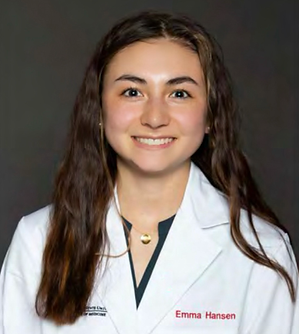 a young brunette woman who is a medical student smiles while wearing a necklace and a medical lab jacket