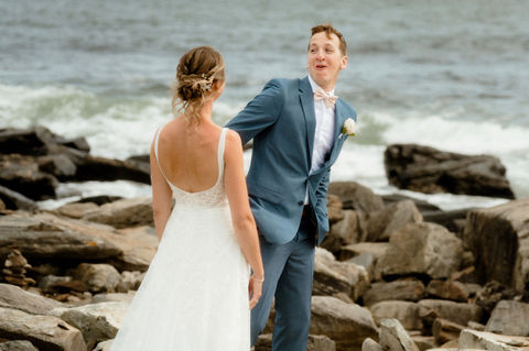 A groom looking shocked as he turns around to see his bride on the coast of Peaks Island in Maine