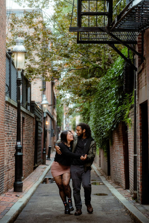 A man and woman walking down a narrow street in downtown Boston.