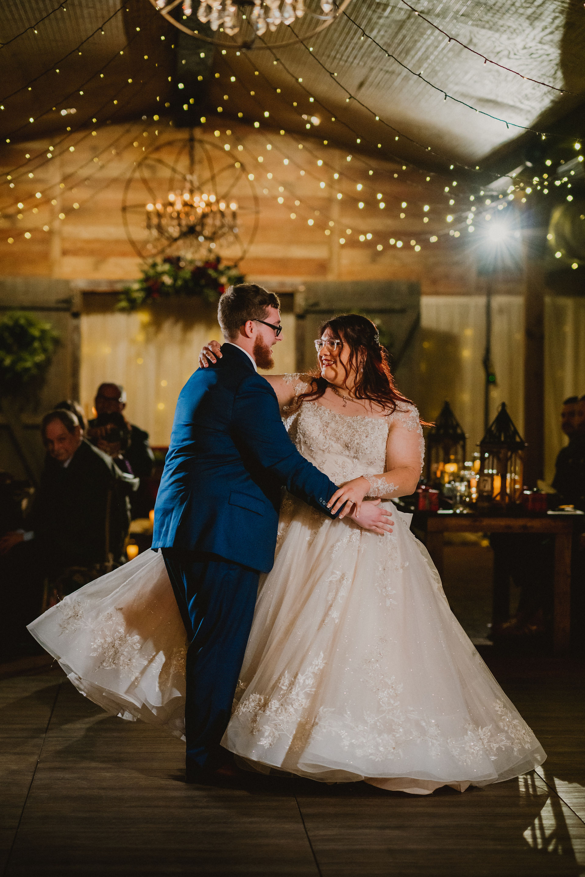 bride and groom first dance in rustic venue with fairy lights