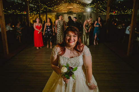 bride looking into camera before bouquet toss at wedding reception