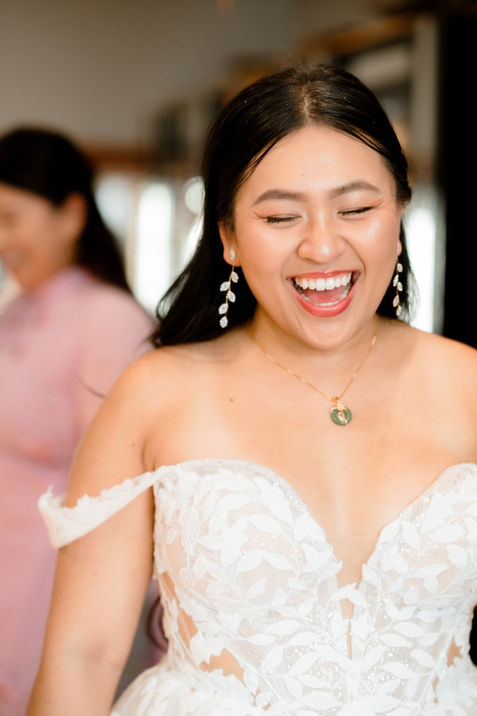 bride candidly laughing while she gets gets ready for her wedding at the lace factory