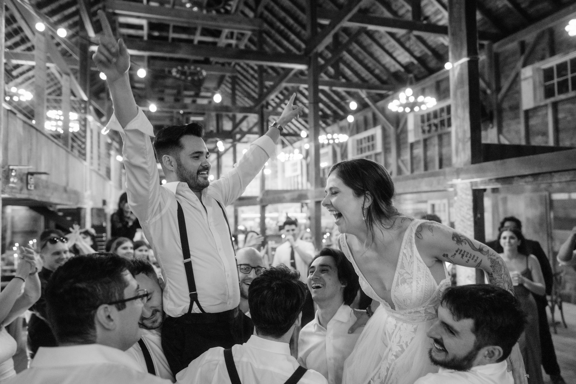 Black and white image of a bride and groom being lifted into the air at a wedding reception in New Hampshire. 