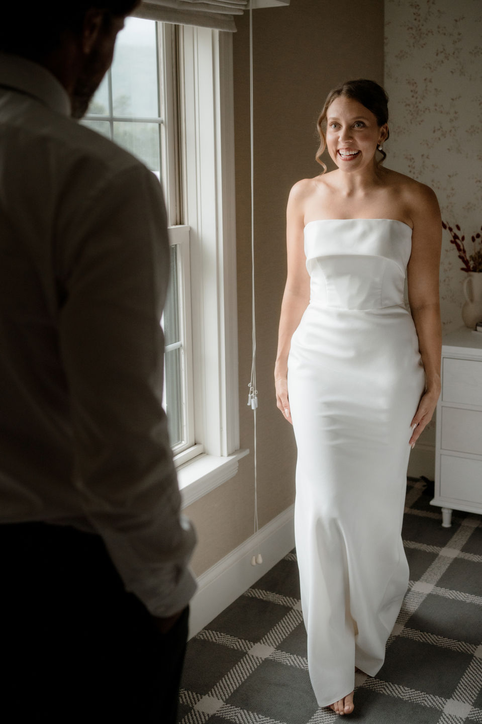 Bride showing off her dress to the groom in a hotel room in New Hampshire.