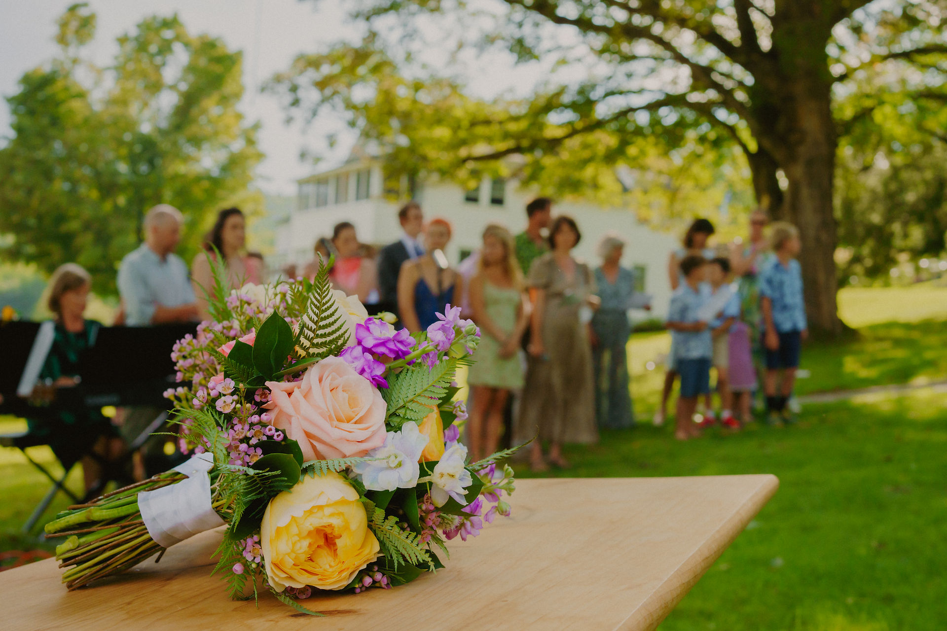 close up image of wedding bouquet with family group gathered in the distance