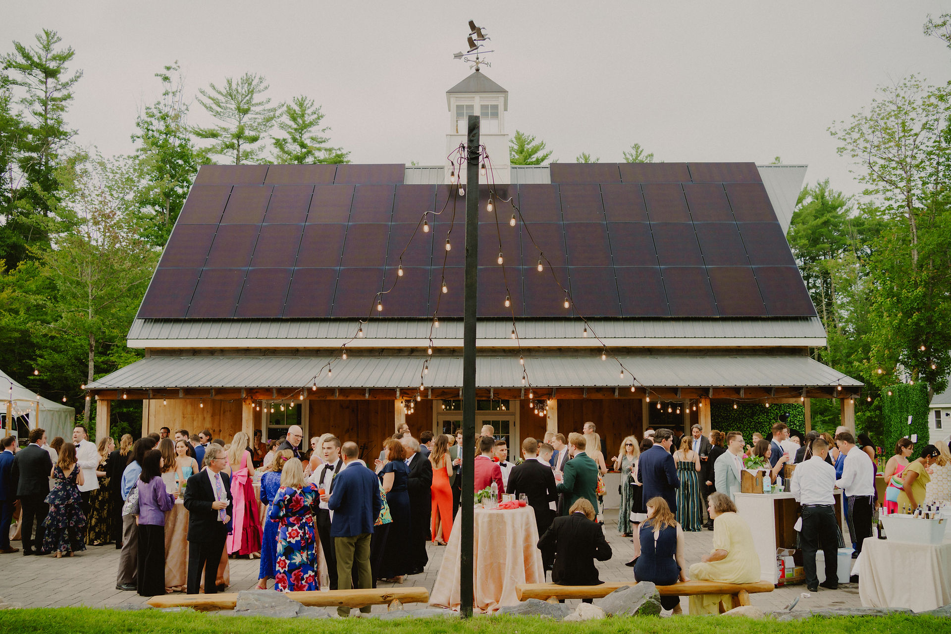 Wide angle view of a wedding reception outdoors next to a barn in Maine