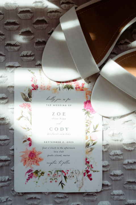 A wedding invitation and shoes taken at Peaks Island in Maine