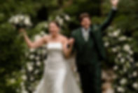 A bride and groom outdoors in a lush green garden in New Hampshire celebrating after their ceremony.