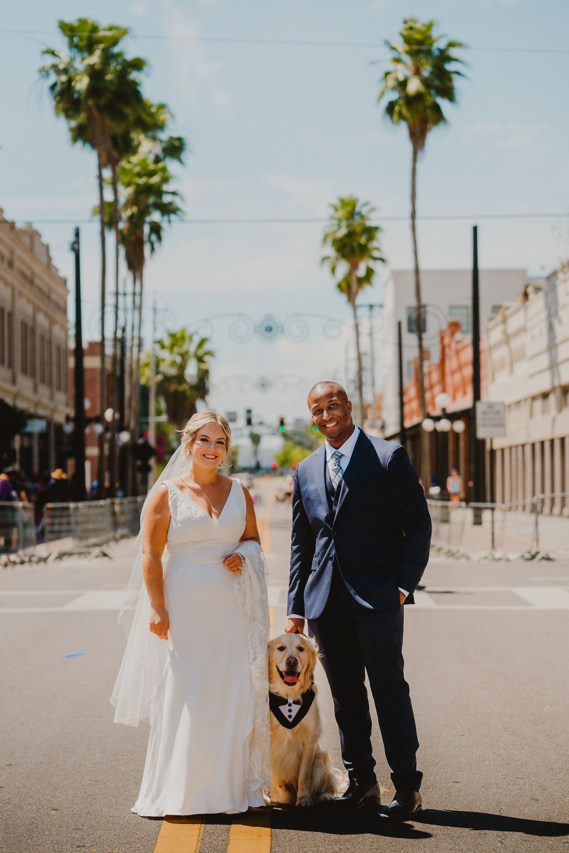 bride and groom standing with dog on 7th Avenue in Ybor City