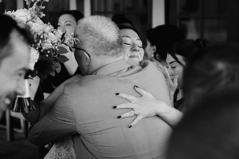 A candid black and white image of a bride hugging her father immediately after their wedding ceremony at the Red Barn at Outlook Farm in South Berwick, Maine