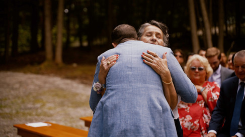 Groom and mom hugging at wedding ceremony in Maine