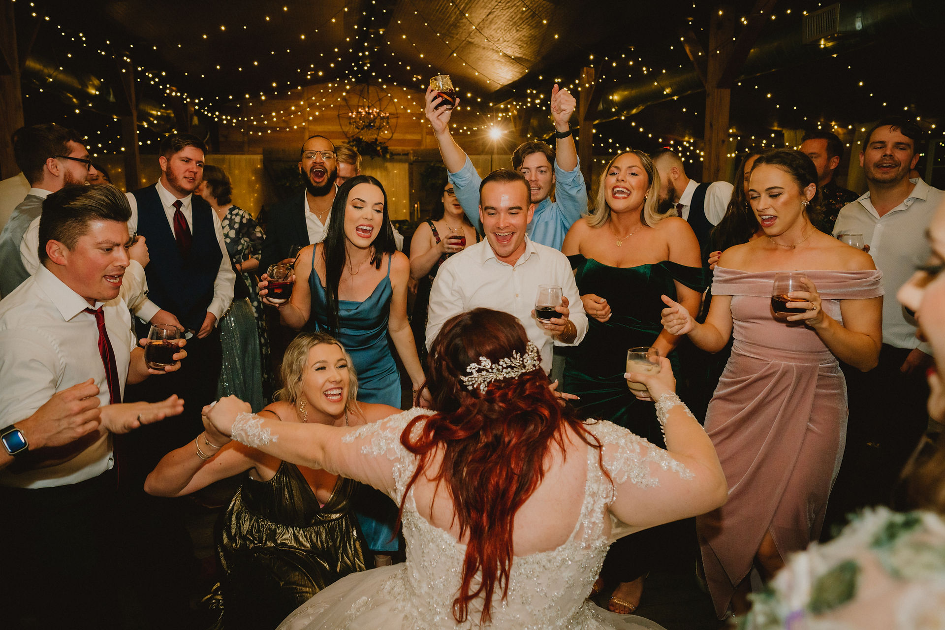 view from behind bride as she dances at wedding reception with crowd surrounding her