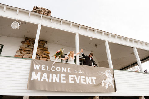 A bride and groom waving from the balcony at TEIA Club on Peaks Island in Maine