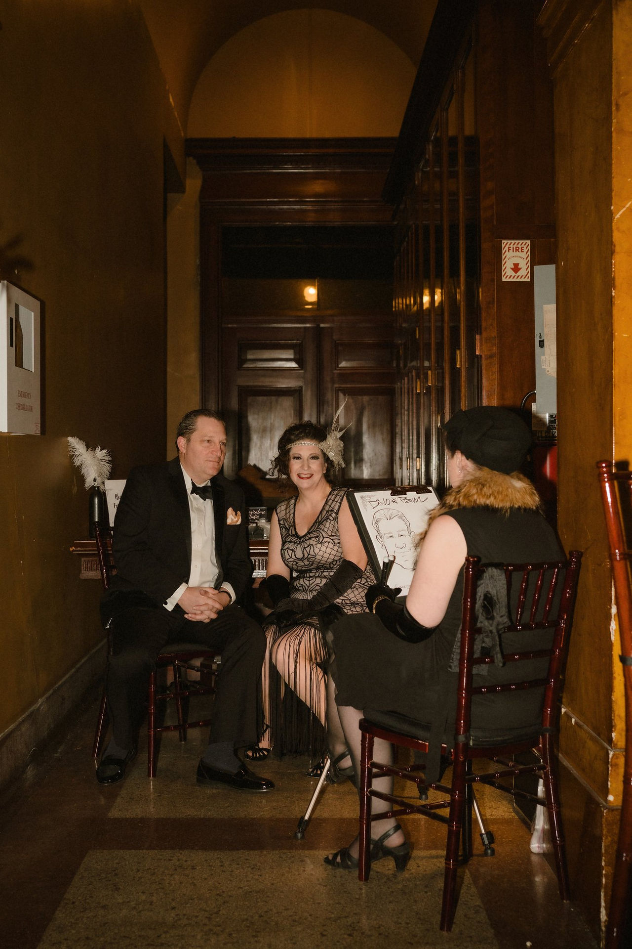 A couple sits in a hallway of The Portland Masonic as they have their caricature drawn in downtown Portland, Maine