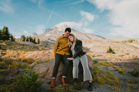 A couple sitting on a rock and leaning against each other at the base of Mt Hood in Oregon.