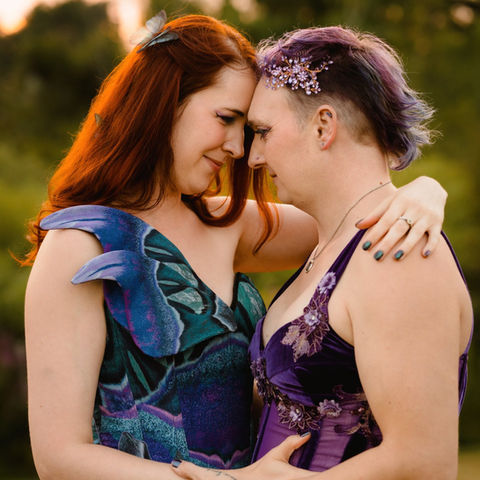Queer brides wearing colorful dresses and embracing at Flaherty Family Farm in Scarborough, Maine