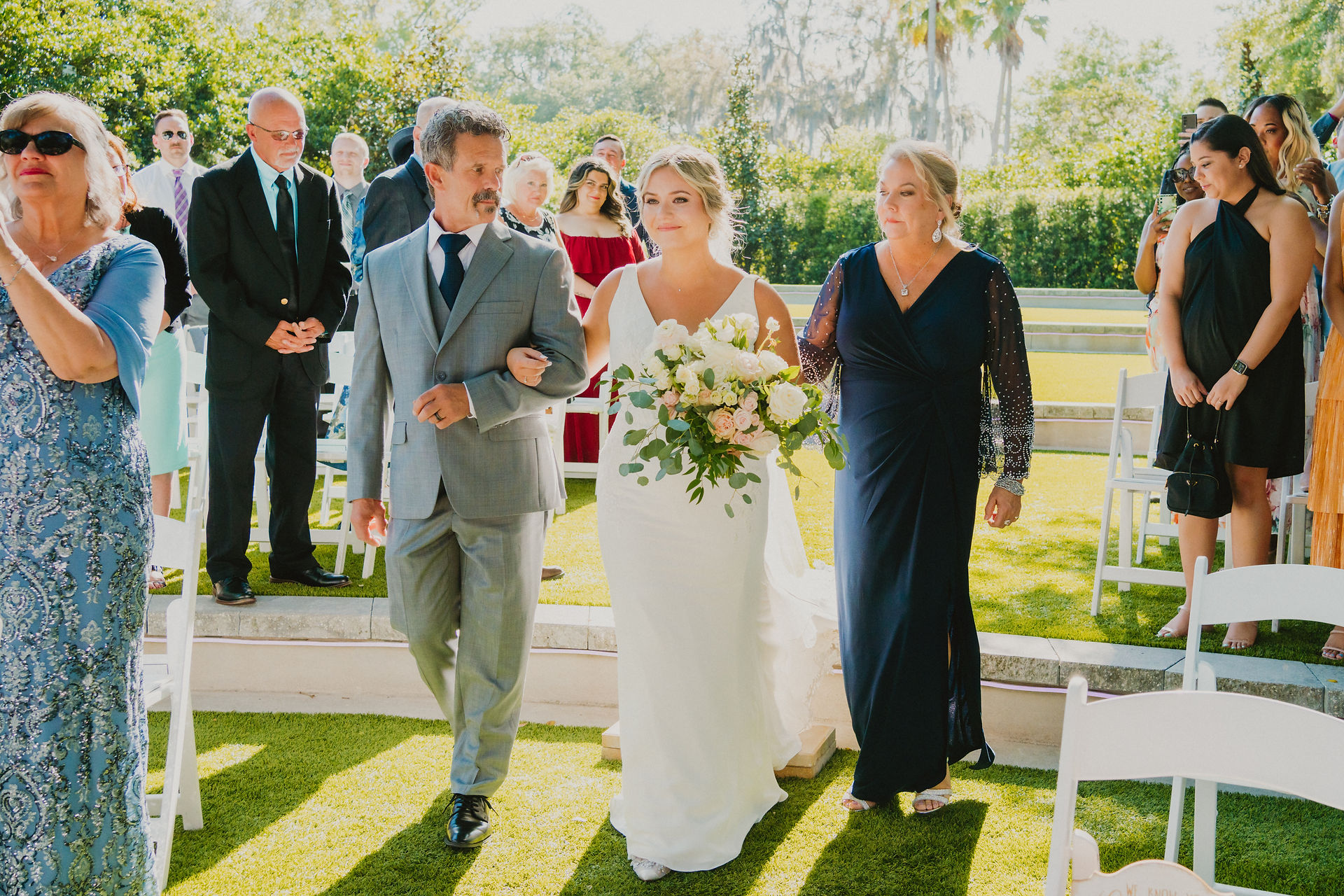 bride walking down the aisle with her parents at outdoor wedding
