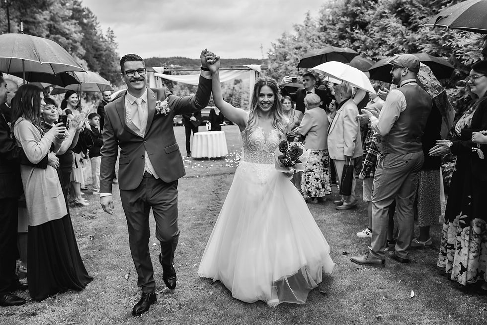 nevesta a ženích pri svadobnej slavobráne, kde prebiehal civilný sobáš v prírode, je to veľmi romantická svadba a romantický svadobný pár, okolo sú svadobčania ktorý im tlieskajú