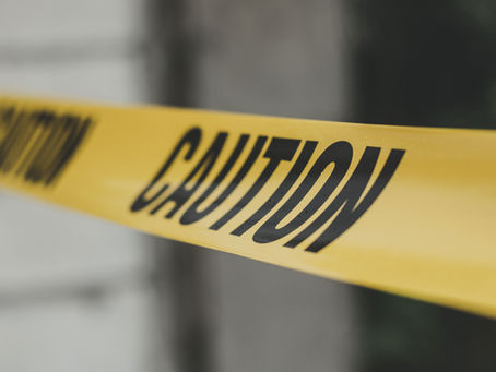 Close-up of yellow caution tape with the word “CAUTION” printed in black, stretched across a blurred background.