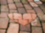 Heart-shaped brick design embedded in a weathered brick walkway, symbolizing love, community, and connection.