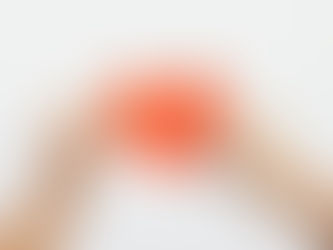 Two hands hold the separated halves of a red paper heart against a plain light gray background.