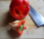 A red bell pepper with the stem removed on a cutting board.