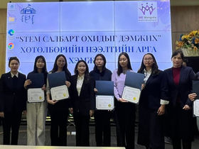 This image shows the opening ceremony of a program in Mongolia aimed at supporting girls in STEM fields. The event is titled "Opening Ceremony of the Program "Empowering Girls in STEM". It is organized by "WE Mongolia," an organization focused on women's empowerment. The scene features participants receiving certificates on stage.