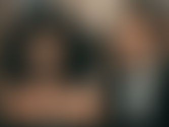 A film still from Moonstruck featuring Nicolas Cage as Ronny Cammareri and Cher as Loretta Castorini. Nicolas Cage, with dark curly hair and a white undershirt, looks intensely at Cher, who has voluminous dark hair and is wearing an elegant black dress.