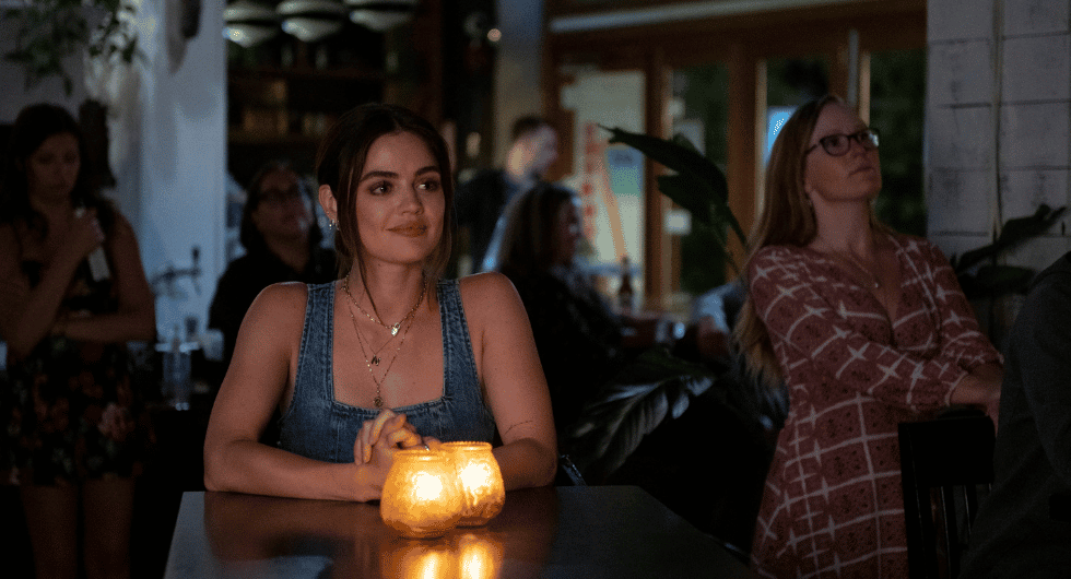 Puppy Love, Lucy Hale as Nicole sits at a restaurant table with candlelight. Photo credit Paulina Stevens.