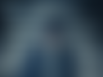 Jamie Bell as Duke Shelby in a dark overcoat and fedora, walking through a misty industrial warehouse in the Peaky Blinders spin-off series.